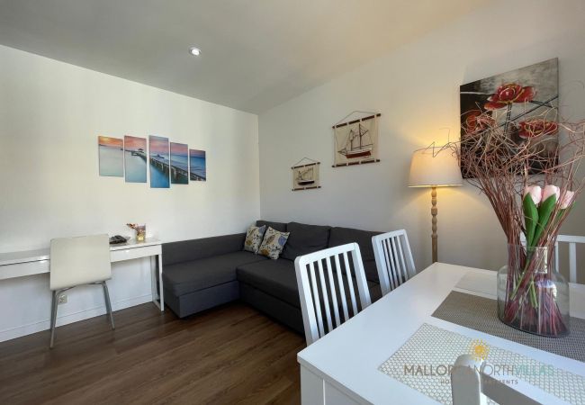 Sala de estar con sofá gris, mesa de comedor blanca, decoración náutica en las paredes y un escritorio con silla blanca.